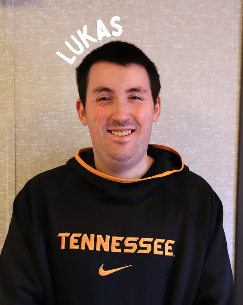 Man smiling in Tennessee hoodie at Riverside Coffee Shop, enjoying a coffee break.