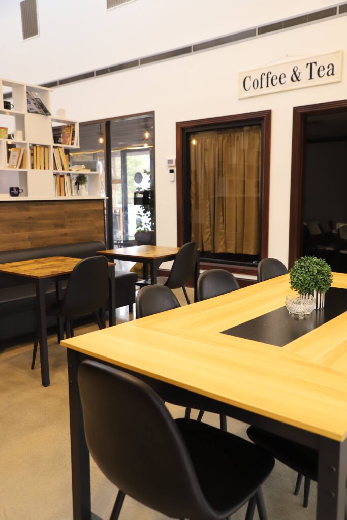Modern coffee shop interior with wooden tables and black chairs.